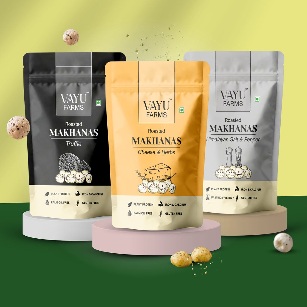 Three stand-up pouches of Vayu Farms Roasted Makhanas — Truffle (black), Cheese & Herbs (mustard yellow), Himalayan Salt & Pepper (silver) — on pastel pedestals against a green-yellow gradient background.